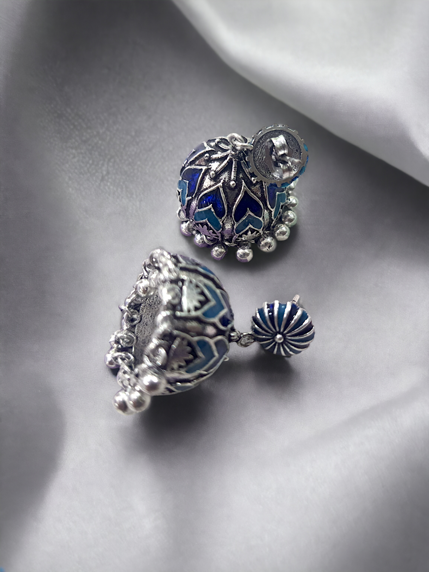 Beautiful Ela enamel jhumka earrings in antique silver, crafted from brass and enamel, designed to elevate your ethnic and festive look. Measuring 4 cm x 2 cm x 1 cm and weighing 28g, these skin-friendly earrings come in Sutra Designs’ custom jewelry packaging, perfect for traditional celebrations