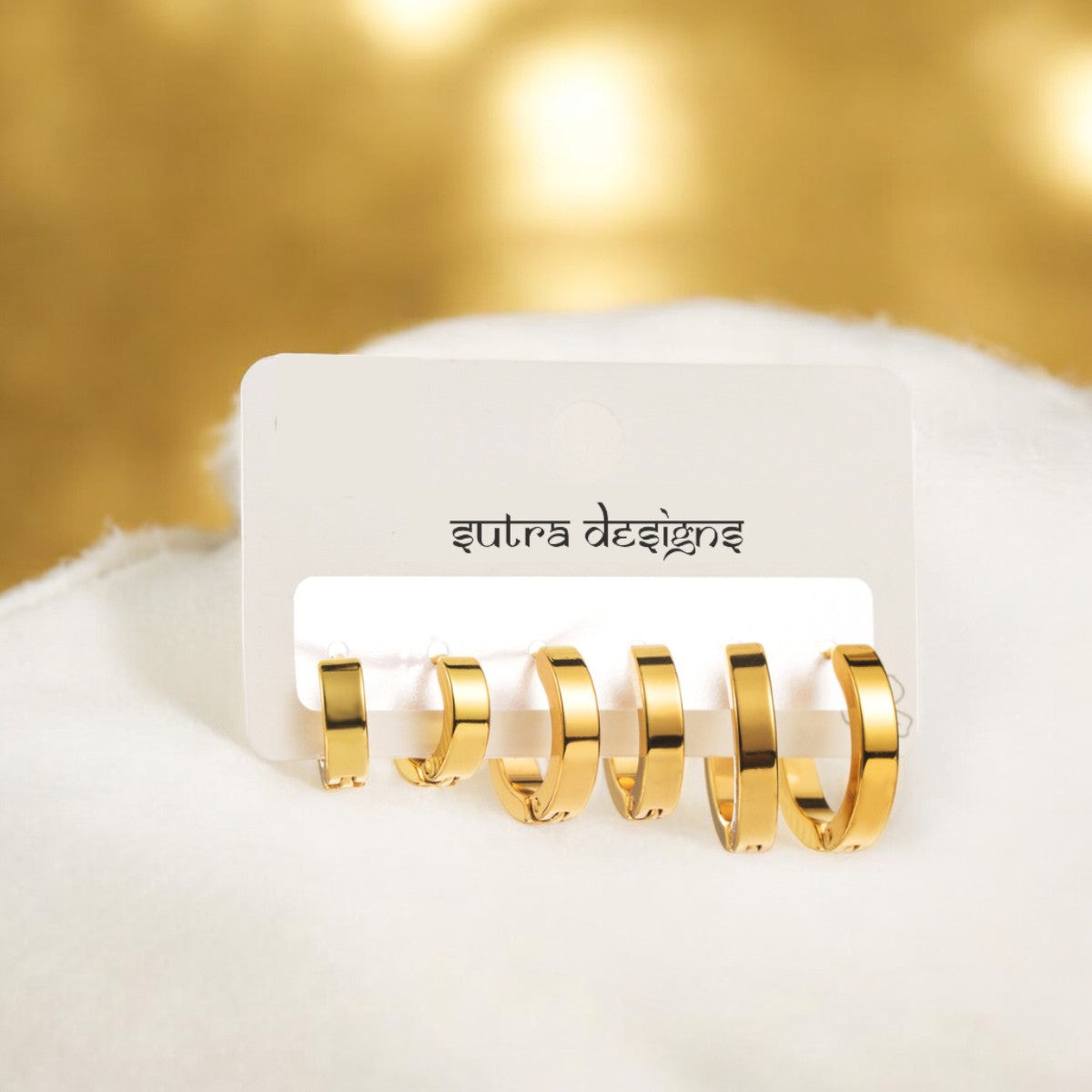Set of 3 18K Gold Plated Hoop Earrings crafted in stainless steel. Includes sizes 1.6cm x 0.3cm, 1.3cm x 0.3cm, and 1.1cm x 0.3cm. Total weight 9g. These hypoallergenic, tarnish-free, and water-resistant earrings offer durable elegance for everyday wear. Versatile and perfect for layering or wearing individually, they add a chic touch to your wardrobe. Delivered in Sutra Designs' custom jewelry packaging for an extra special experience