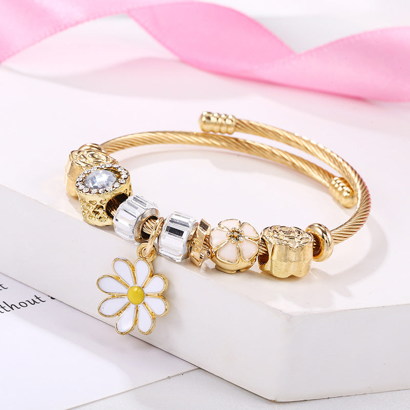 Flower Charm Enamel Bangle in Gold-Plated Titanium Steel. Adjustable size 5.5 with a weight of 17.5g. Hypoallergenic, tarnish-free, water-resistant, and delivered in Sutra Designs' custom packaging