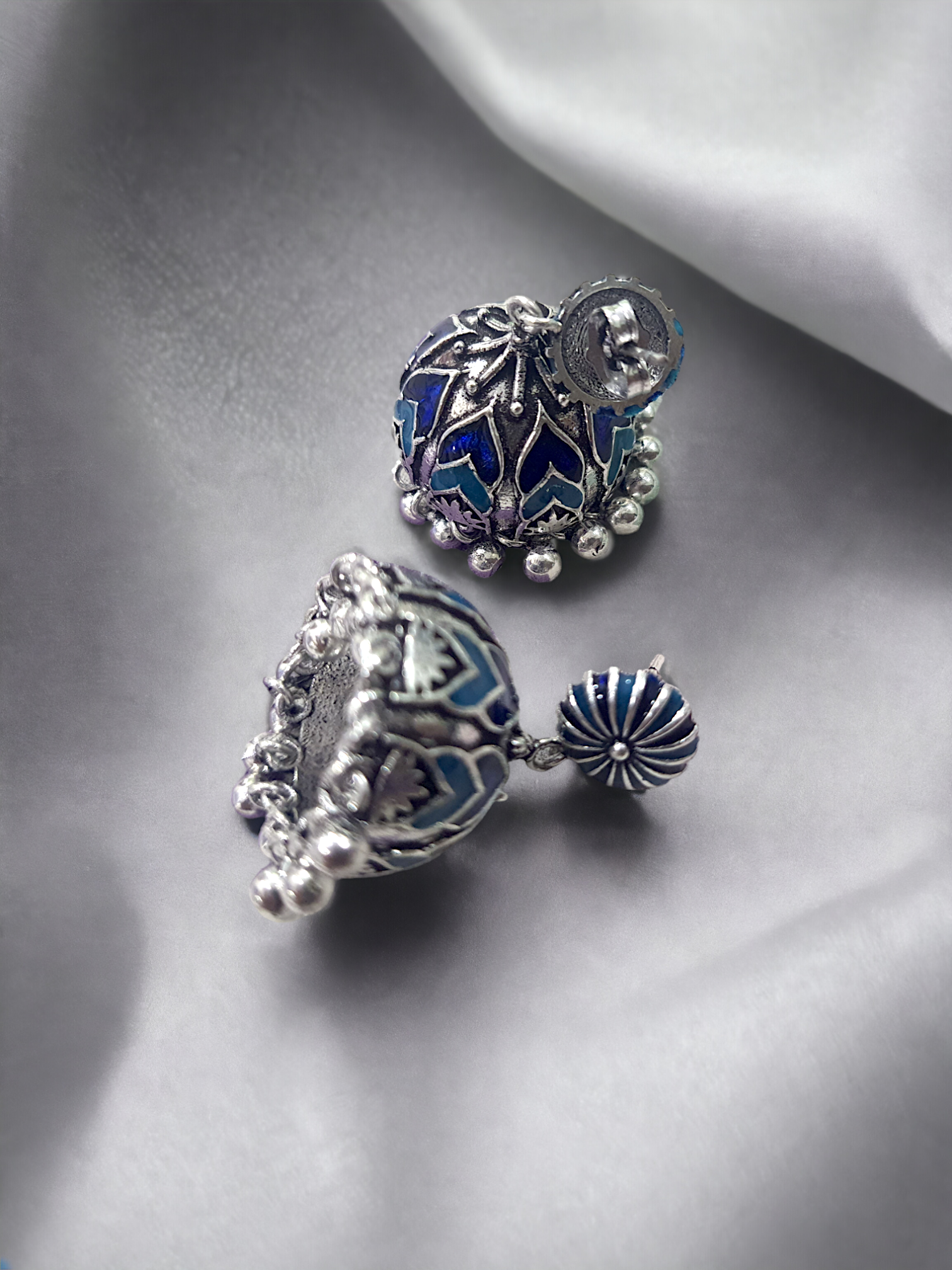 Beautiful Ela enamel jhumka earrings in antique silver, crafted from brass and enamel, designed to elevate your ethnic and festive look. Measuring 4 cm x 2 cm x 1 cm and weighing 28g, these skin-friendly earrings come in Sutra Designs’ custom jewelry packaging, perfect for traditional celebrations